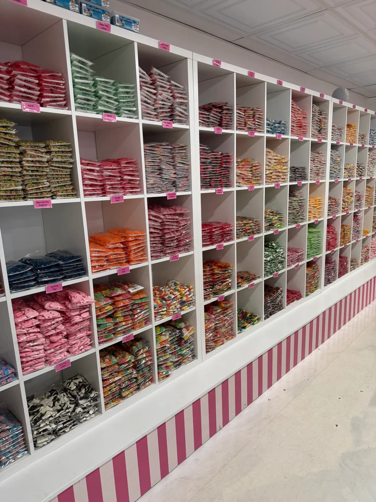 Cubbies filled with bagged candy along a pink-striped wall