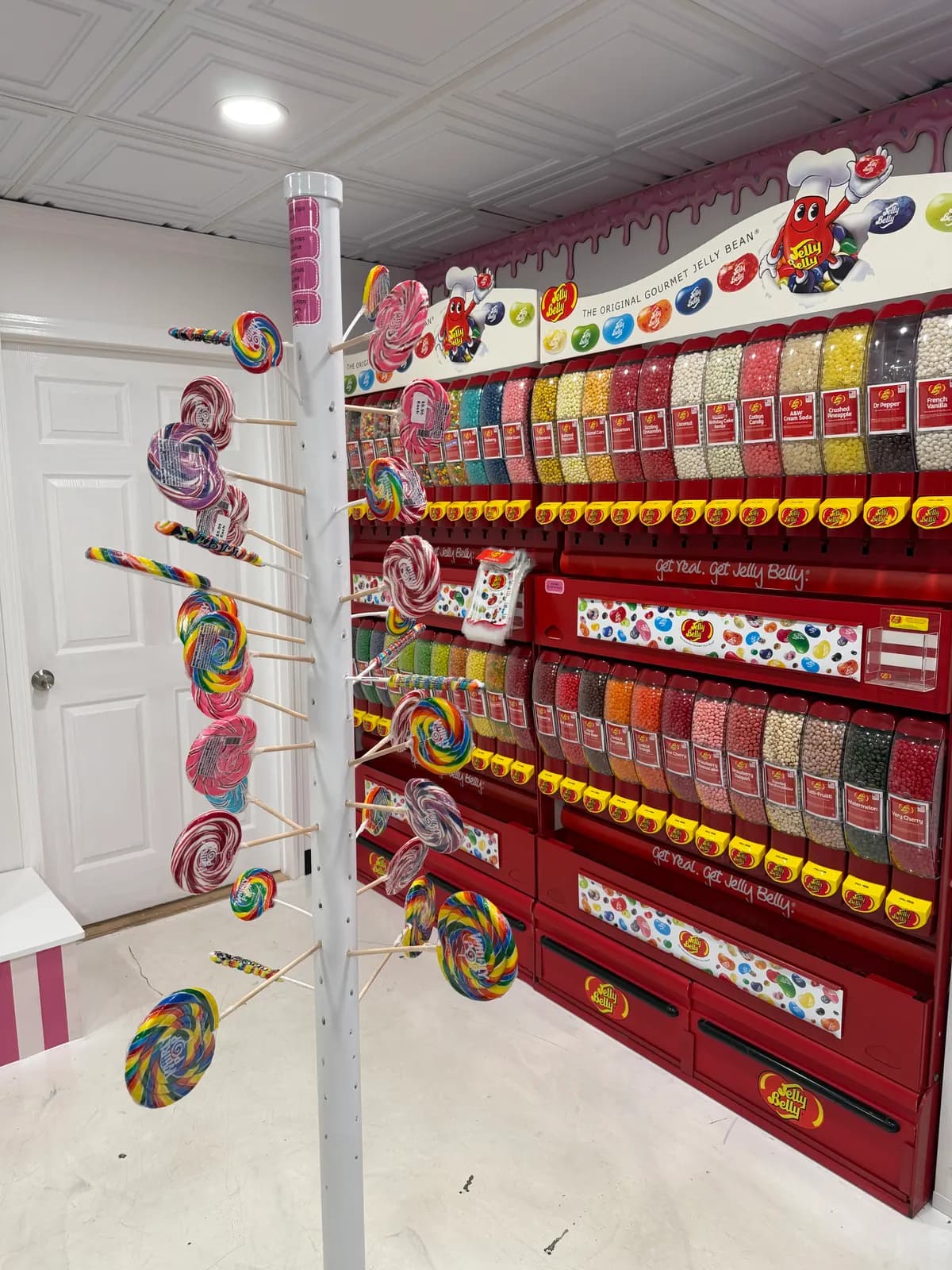 Wall of Jelly Belly jellybean dispensers with whirly pops hanging in front